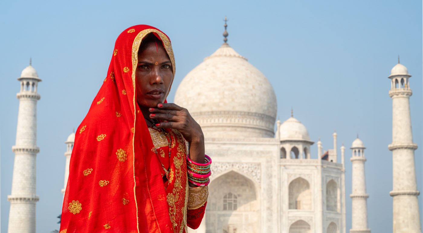 Mulher de sári vermelho diante do Taj Mahal